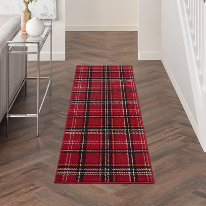 Red plaid runner rug with black and white stripes in a modern hallway on herringbone wood floor.