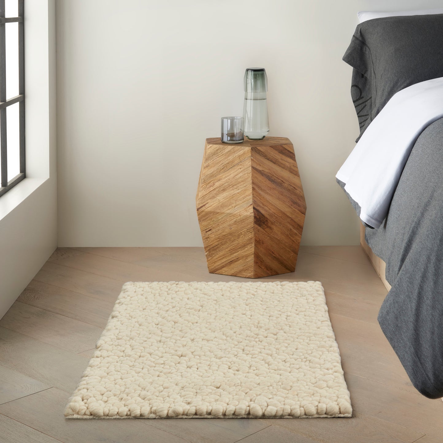 Geometric rug on a light wood floor in cream and gray tones.