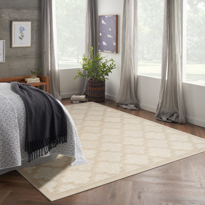 Neutral beige patterned area rug on wood floor; gray throw, airy curtains, and a potted plant in a woven basket.