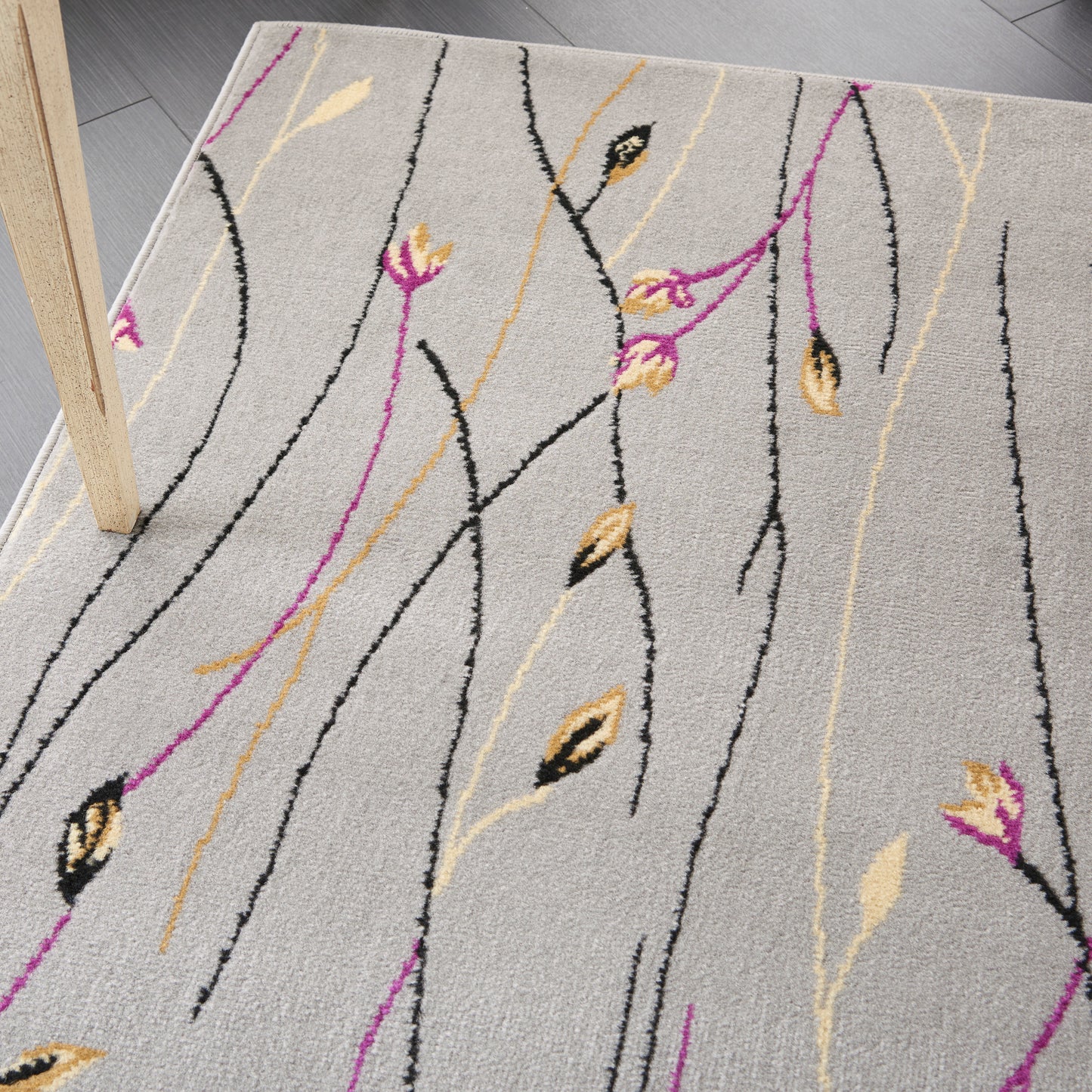 Soft textured light-gray area rug with black, gold and magenta linear stems and leaf accents; contemporary floral design.