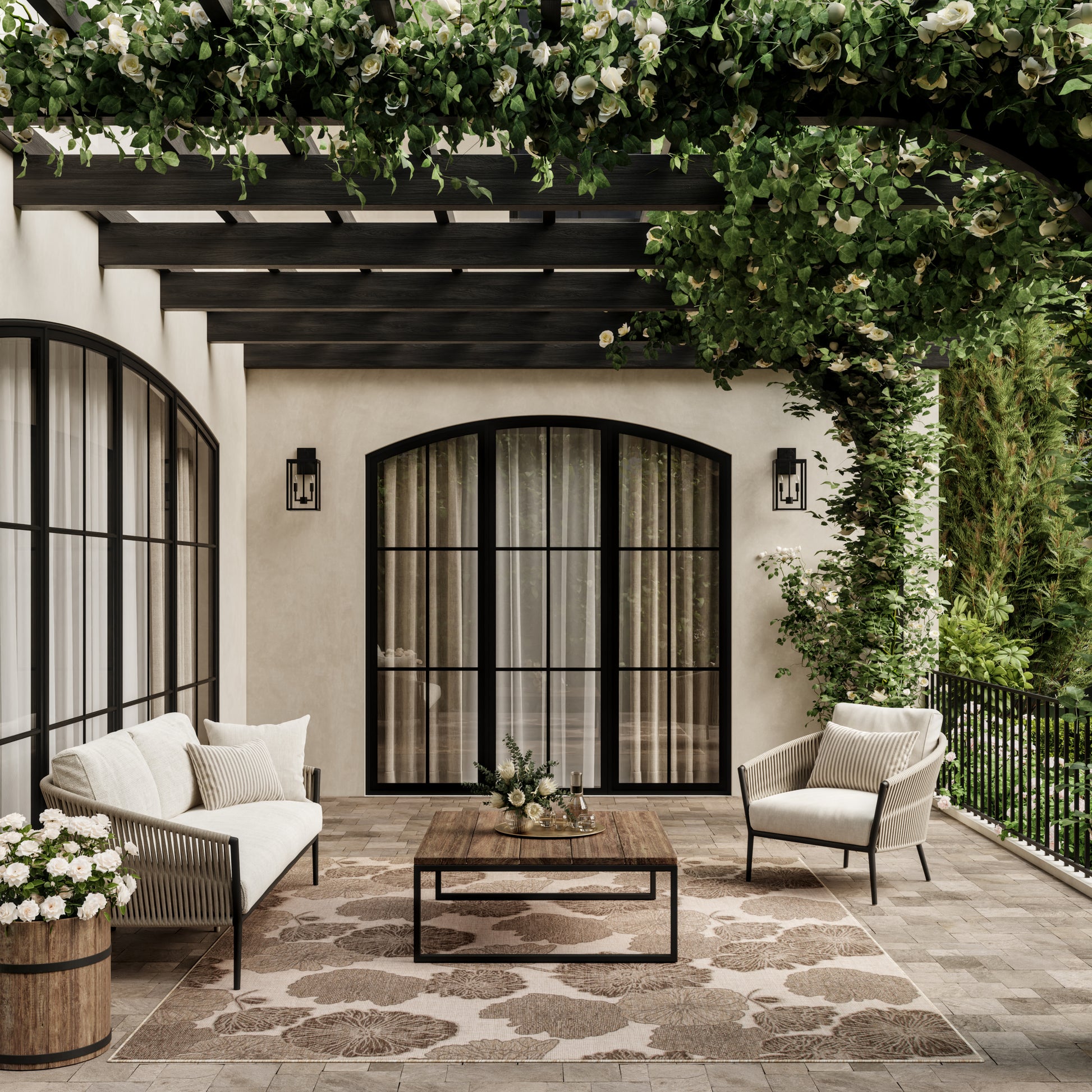 Cozy outdoor patio with glass doors, cream cushioned rattan seating, wooden coffee table, lush greenery overhead.