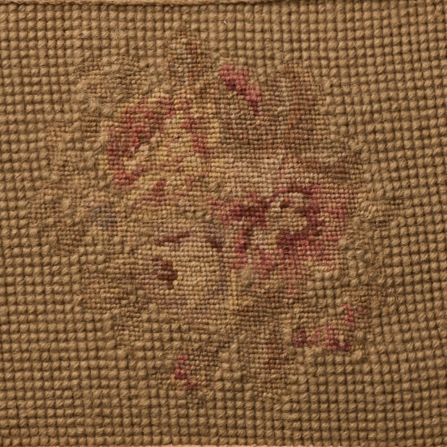 Coarse brown burlap fabric featuring a faded vintage floral pattern in red and beige.