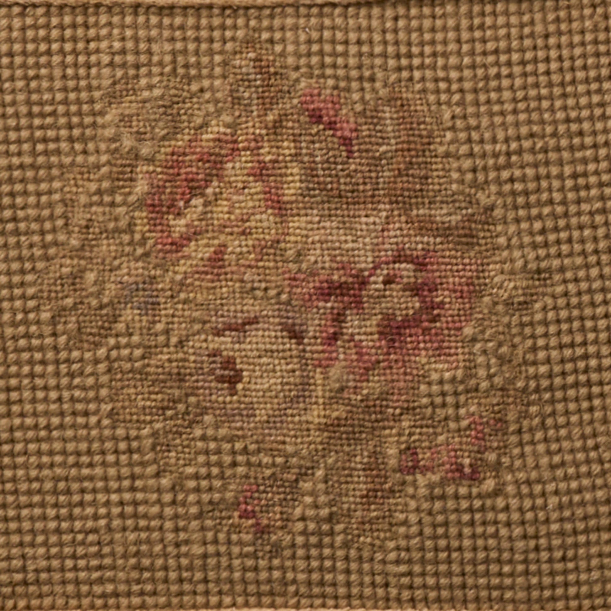 Coarse brown burlap fabric featuring a faded vintage floral pattern in red and beige.
