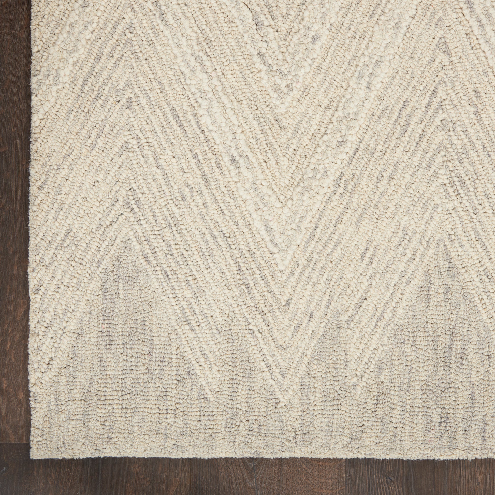 Cream textured shag rug with chevron pattern on dark wood floor, cozy coastal style.