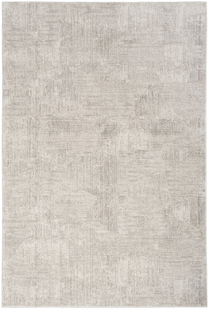Neutral beige area rug with a subtle geometric patchwork pattern in taupe-gray tones.