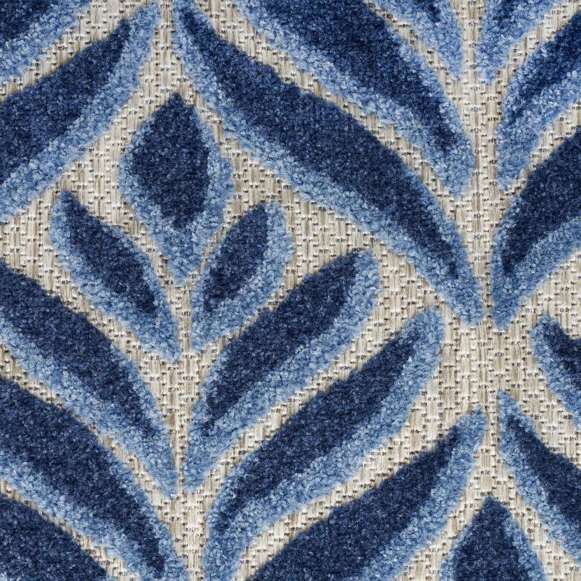 Blue leaf-pattern area rug with navy and light-blue fronds on beige woven backing.