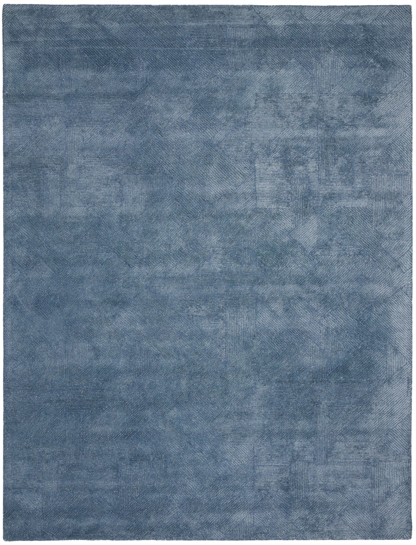 Blue rectangular rug with patchwork-like textures in varied denim tones; soft woven look.