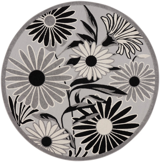 Round gray rug with bold black-and-white daisies and leaf motifs.