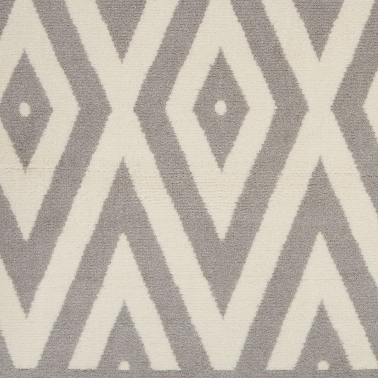 Grey and ivory chevron rug with diamond motifs; textured woven fabric.