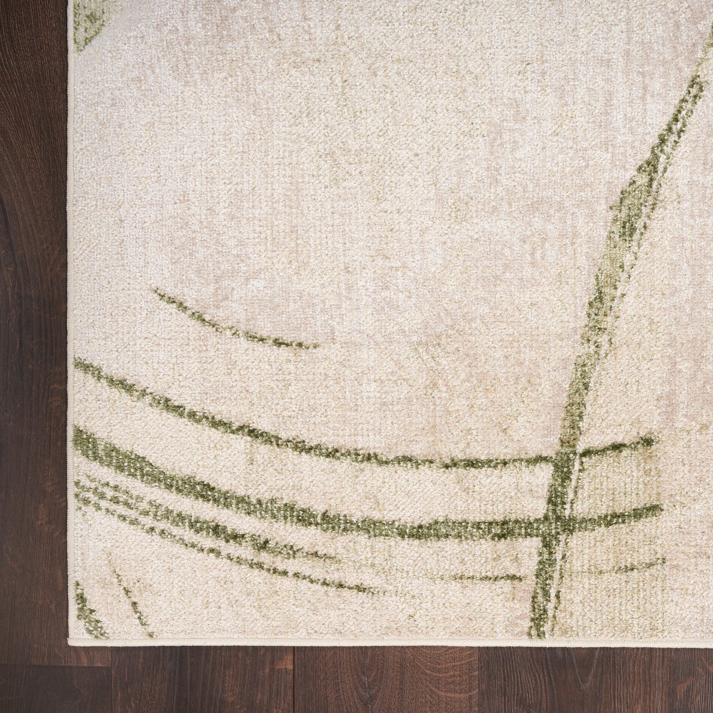 Beige rectangular rug with abstract green curved lines on a dark wooden floor.