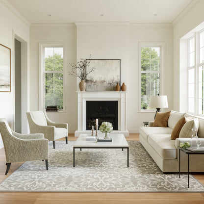Cream sofa, pale patterned chairs, white coffee table, light floral rug, fireplace with art and vases in a living room.