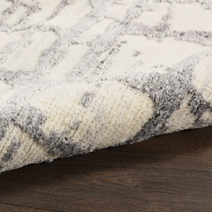 Close-up of a cream and gray shag rug with a geometric pattern on dark wood floor.