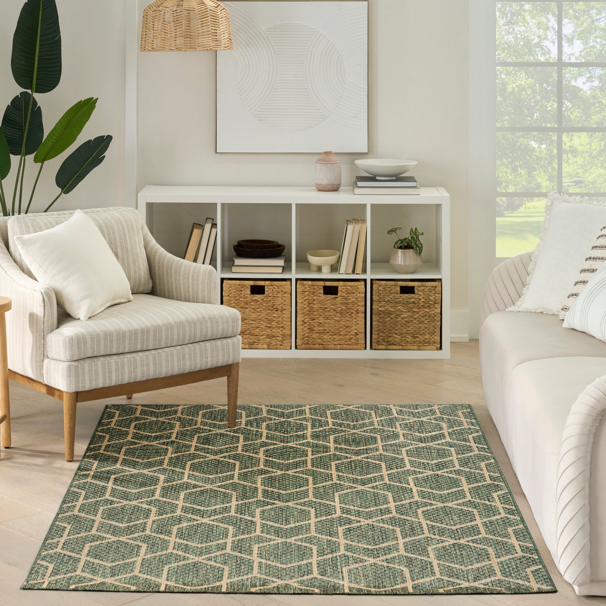 Neutral living room with white cube storage, beige armchair, green geometric rug, potted plant, wicker pendant light.