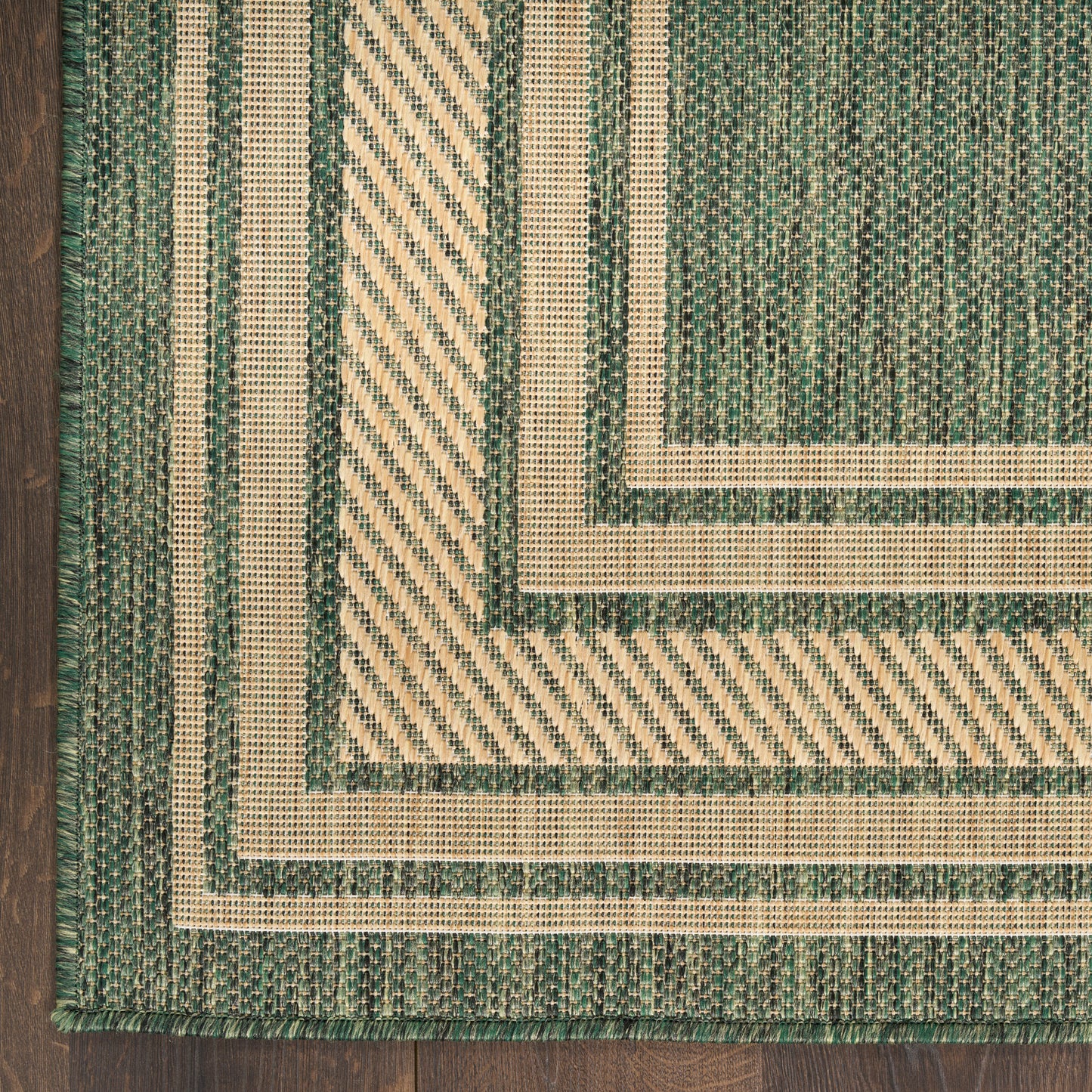 Woven green and cream rug with nested rectangular borders and diagonal striped detailing.