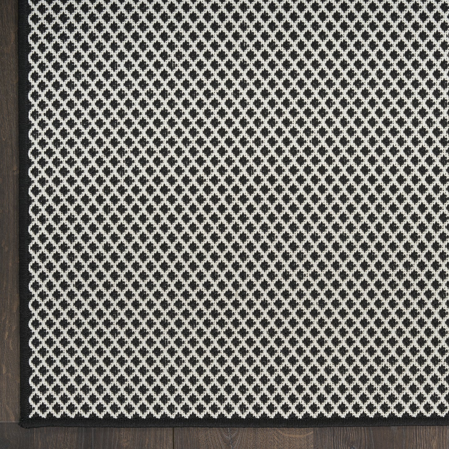 Black and ivory diamond-patterned runner rug with a slim black border and woven texture, ideal for living room accents.