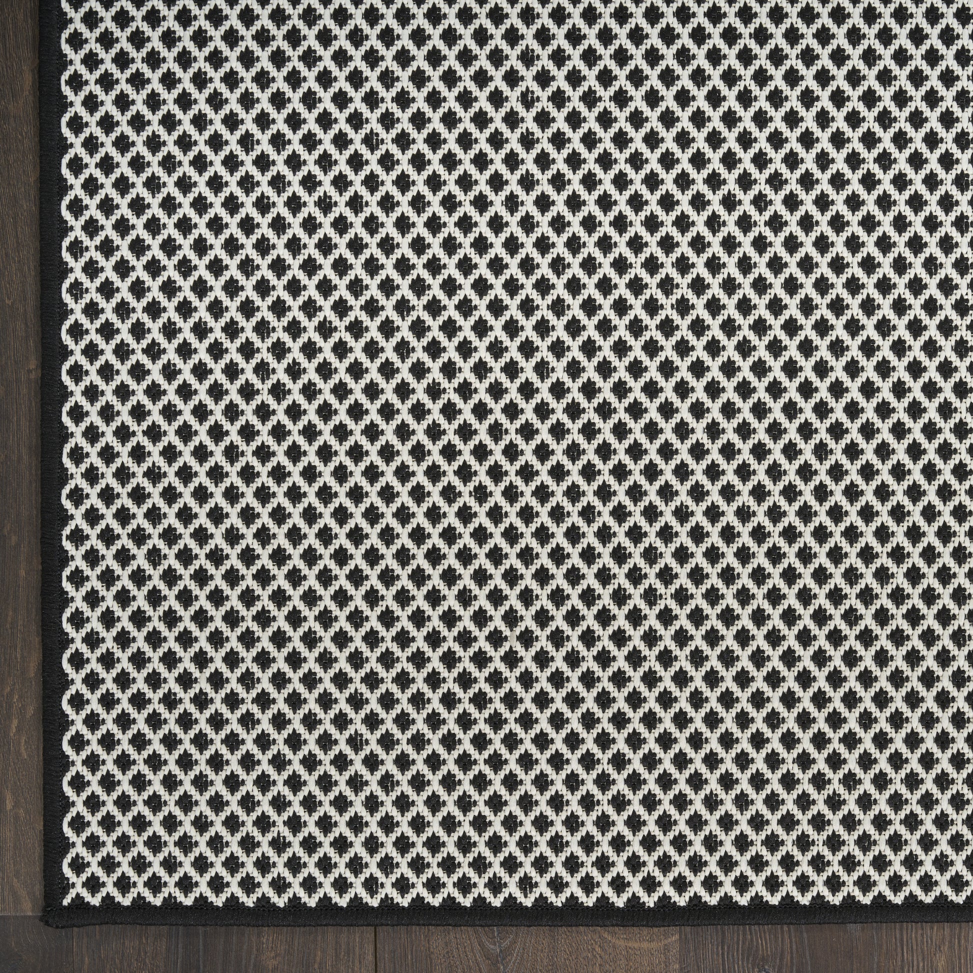 Black and ivory diamond-patterned runner rug with a slim black border and woven texture, ideal for living room accents.