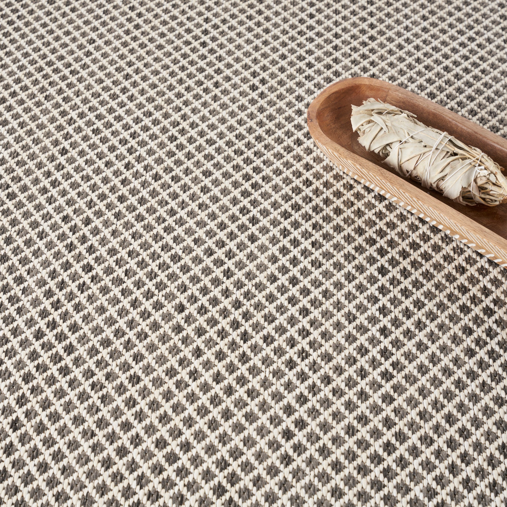 Beige rectangular sheet of paper on a black-and-white diamond-patterned carpet.