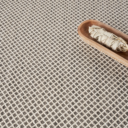 Beige rectangular sheet of paper on a black-and-white diamond-patterned carpet.