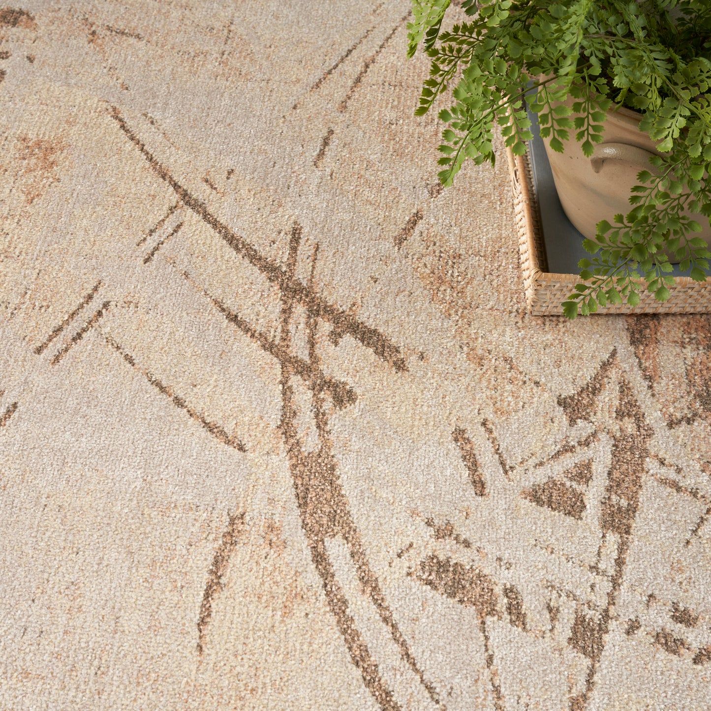 Beige textured rug with brown abstract geometric lines; potted green fern in a woven basket at the corner.