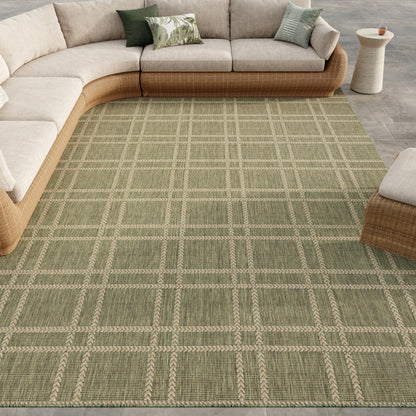 Green plaid area rug with beige grid lines under a beige modular sectional with wicker frame and green accent pillows.