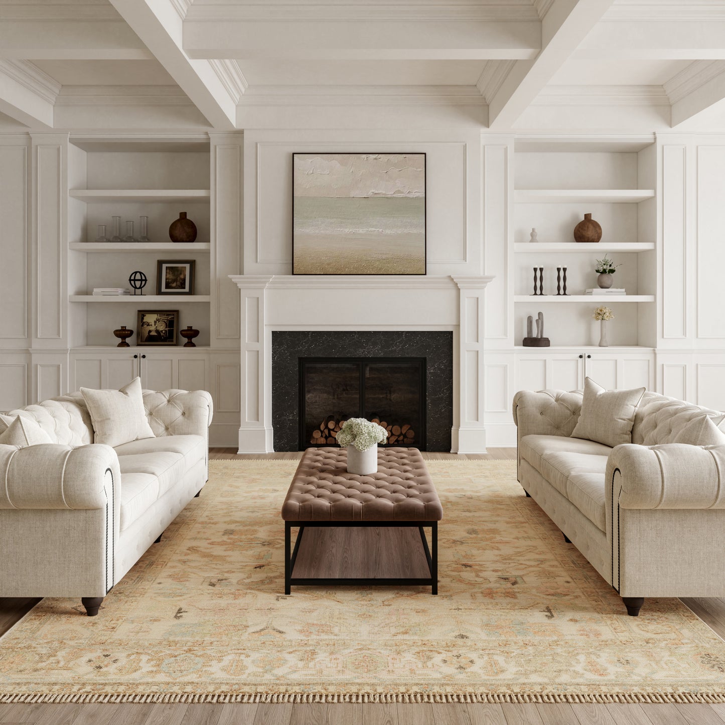 Neutral living room with cream tufted sofas facing a brown tufted ottoman, white built-in shelves, and a fireplace.