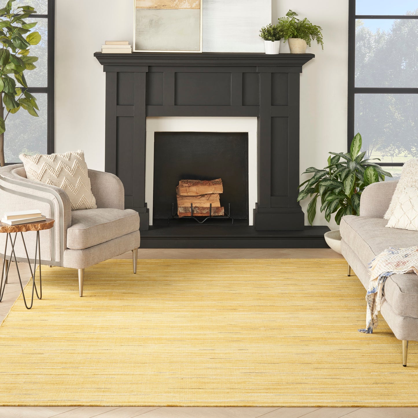 Black wooden mantel with paneled details, beige armchairs, a yellow rug, and leafy plants in a sunlit living room.