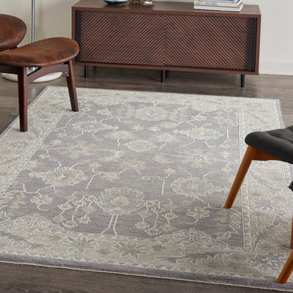 Gray floral area rug on dark wood floor with cream border; vintage 5' x 8' rug.