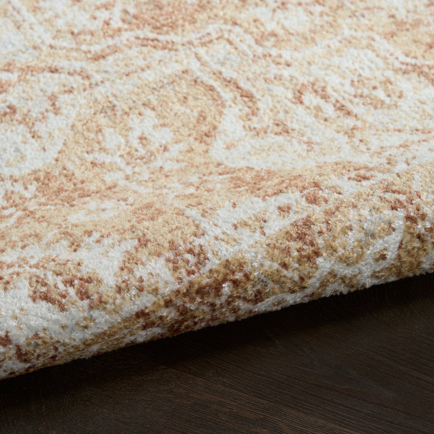Beige ivory patterned rug with tan accents, plush pile, rolled edge on dark wood floor