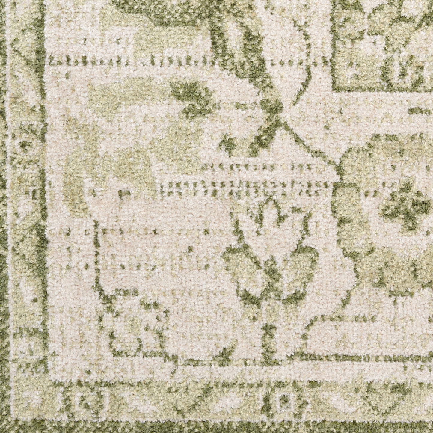 Close-up of a beige-green textured rug with floral motifs and a decorative border.