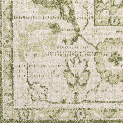 Close-up of a beige-green textured rug with floral motifs and a decorative border.