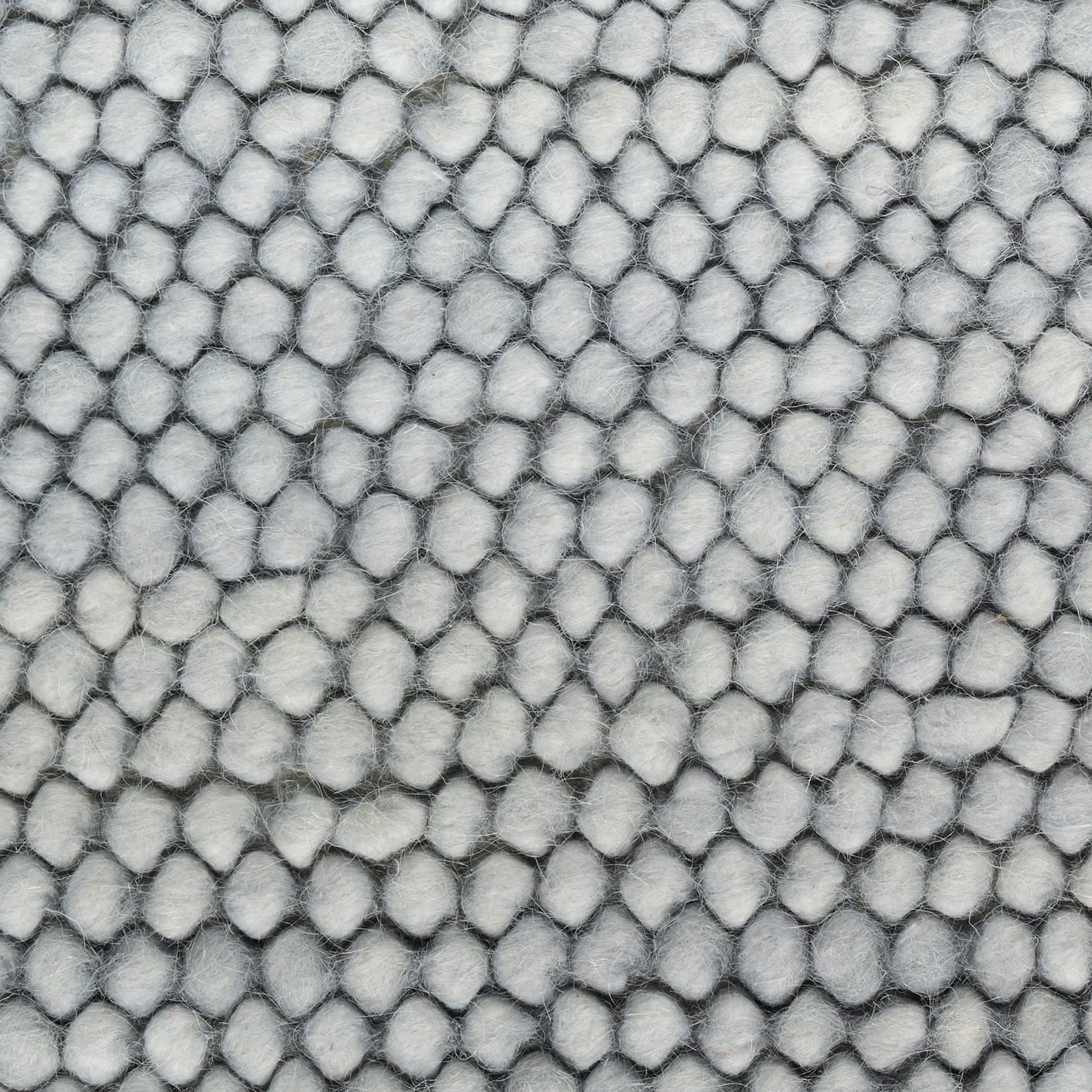 Close-up of light gray pebble-textured fabric with small rounded bumps; plush upholstery material.