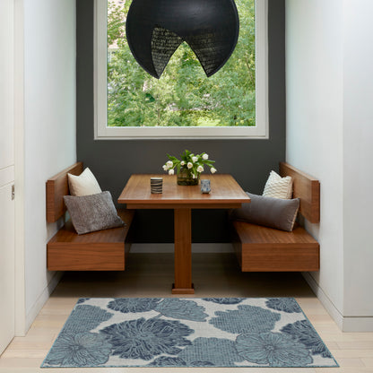 Warm wooden corner dining nook with built-in benches, square table, blue floral rug, white flowers, and black dome pendant.