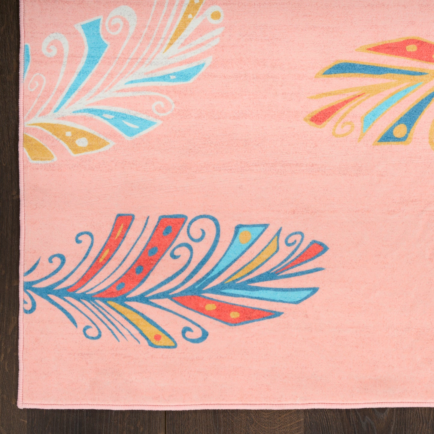 Pink kids rug with bold blue, yellow and orange leaf motifs; boho style.