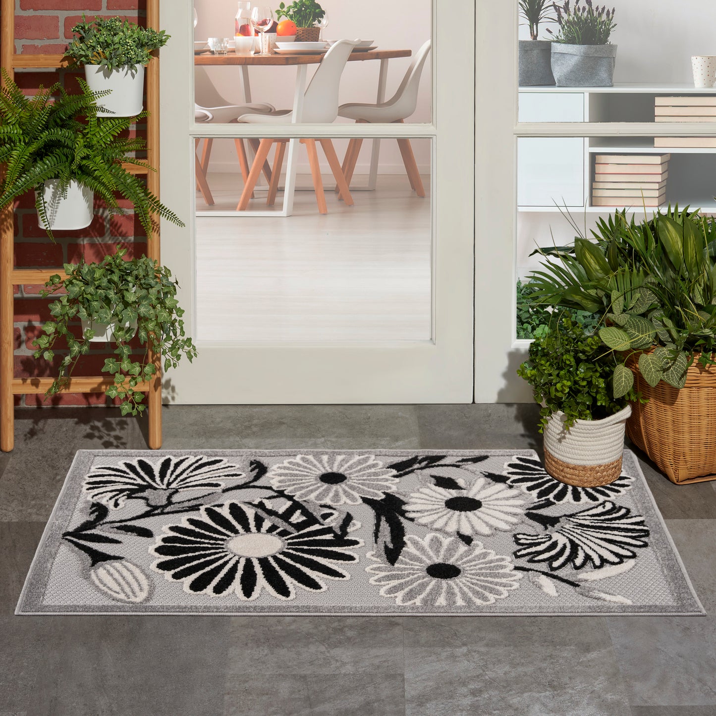 Rectangular entry rug with bold black-and-white floral print on gray background; woven fabric, ideal for foyer or doorstep.