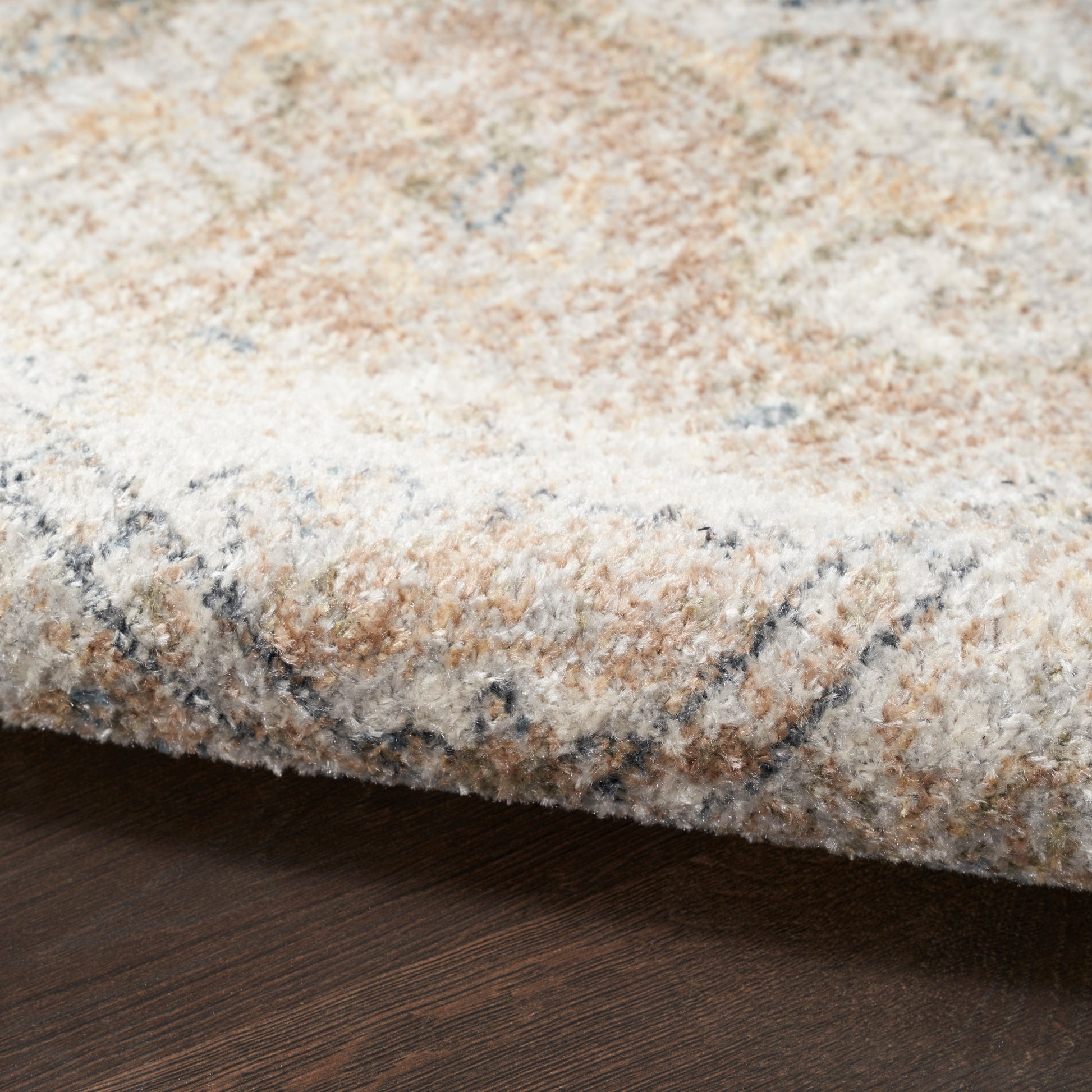 Cream beige textured rug with soft pile and subtle blue-gray pattern on dark wood floor.