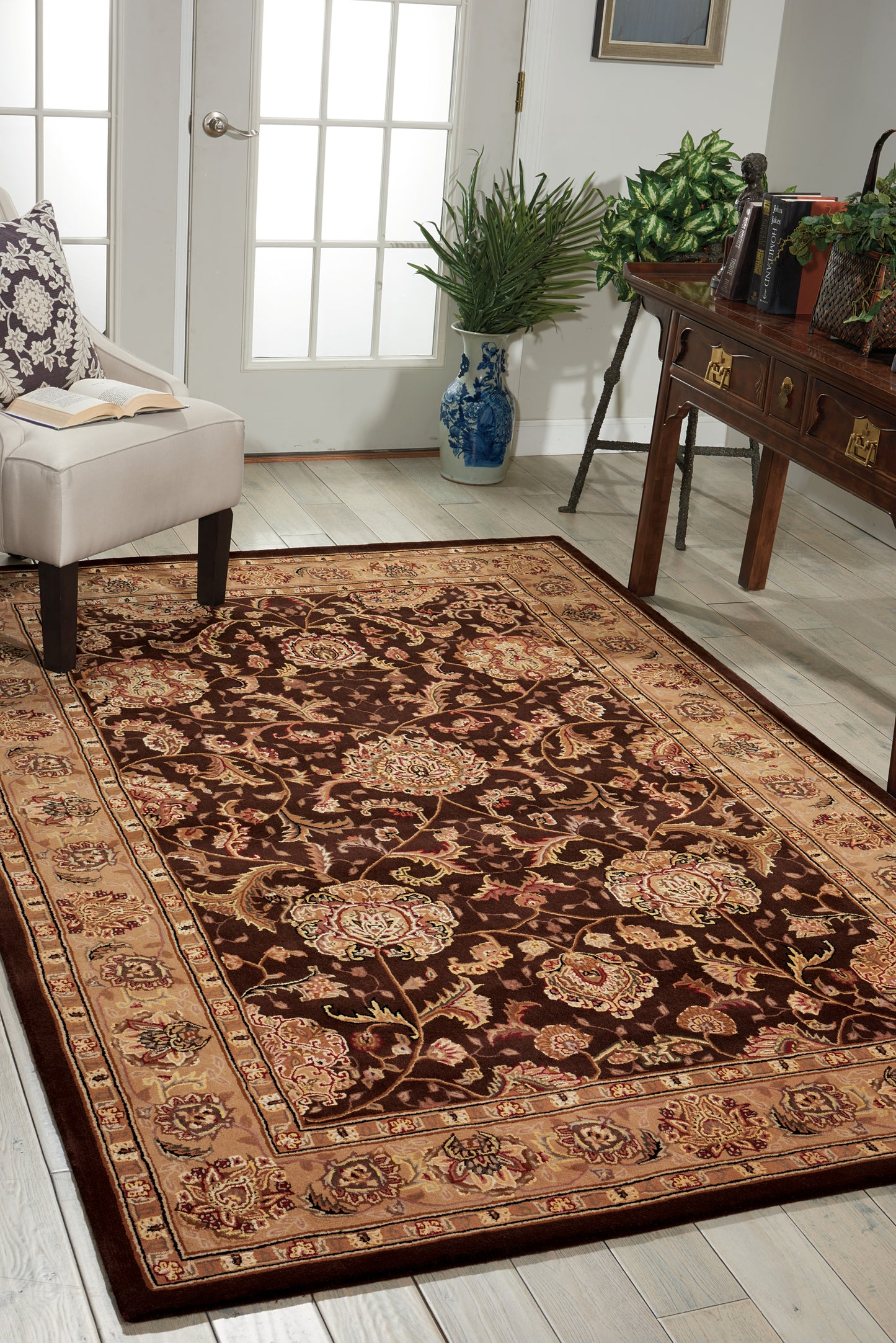 Persian-style area rug with burgundy field, cream-and-gold florals and beige border in a bright living room.