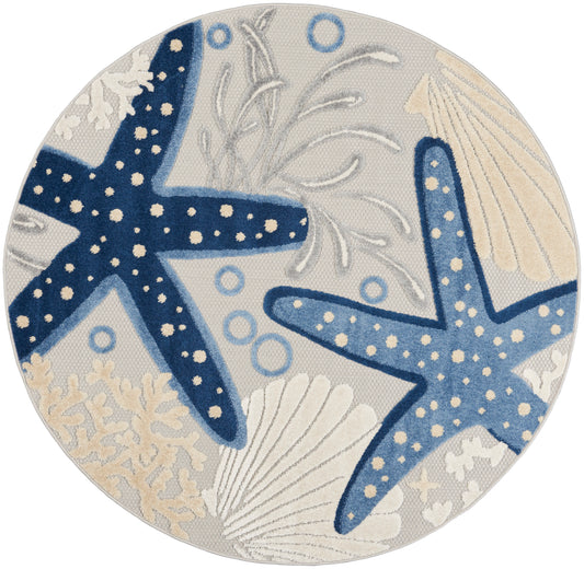 Round coastal rug with navy and light blue starfish, seashells, coral and bubbles in beige and blue tones.