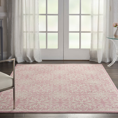 Pink patterned area rug with white floral motif in a bright room with French doors.