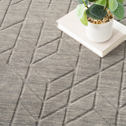 Gray geometric area rug with raised diamond pattern; white ceramic planter on a matching white tray.