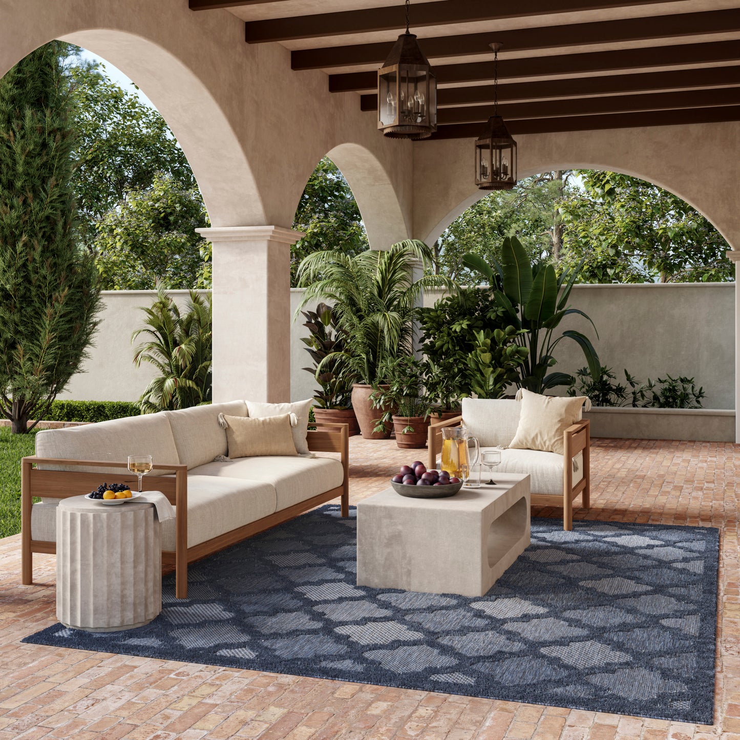 Outdoor patio with beige cushioned wooden sofas, blue patterned rug, concrete coffee table, potted plants, arched columns.