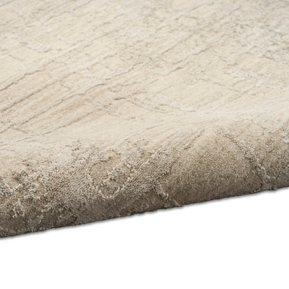 Beige plush area rug with subtle scroll pattern & soft thick pile, rolled edge.