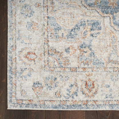 Rectangular distressed oriental rug in ivory, light blue, tan and rust on dark hardwood floor.