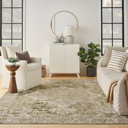 Neutral living room with cream sofa, beige armchair, round mirror, geometric white cabinet, lamp, vases, and green rug.