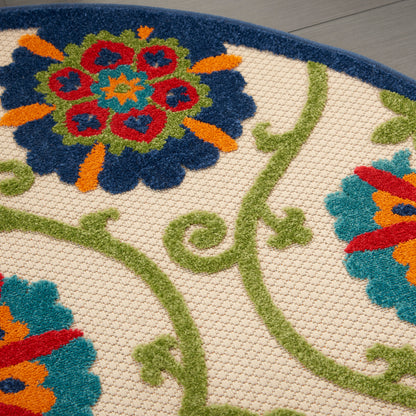 Close-up of a beige textured rug with green vines and vibrant blue, red, orange, teal floral motifs.
