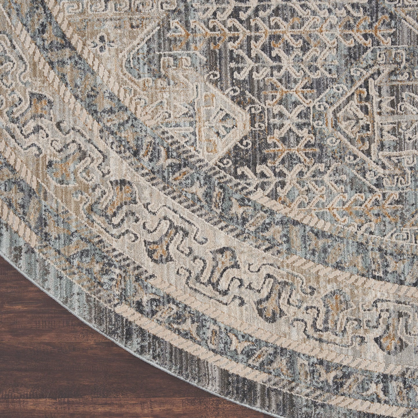 Round oriental rug in blue, ivory, and gray with medallion and border patterns on dark wood floor.
