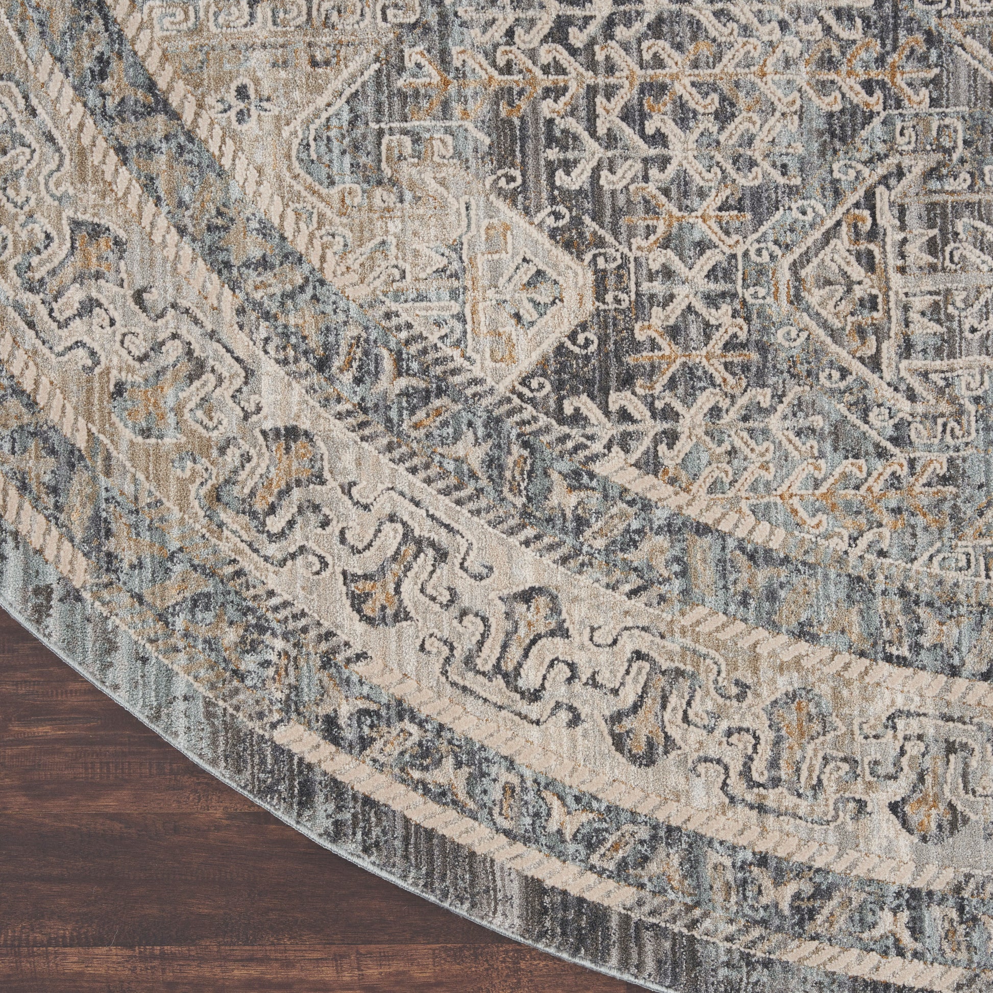Round oriental rug in blue, ivory, and gray with medallion and border patterns on dark wood floor.