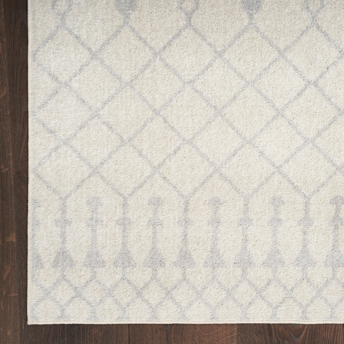 Cream tufted rug with pale blue lattice pattern and arched border on dark wood floor