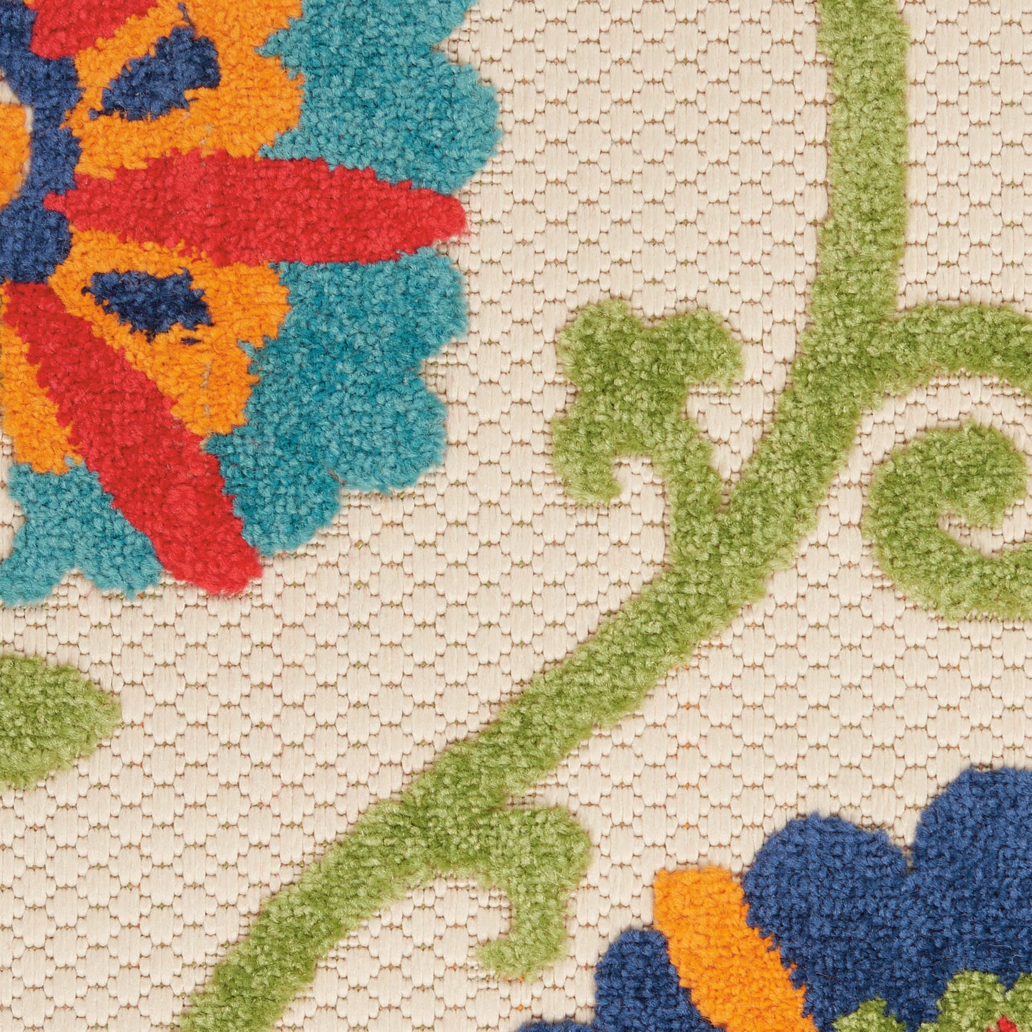 Beige tufted rug featuring vibrant multicolor flower motifs (red, orange, blue, turquoise) with green vines; textured yarn.
