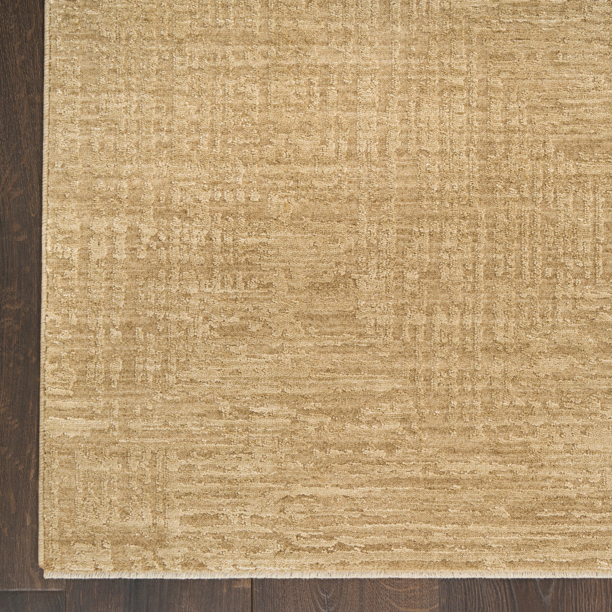 Beige textured area rug with subtle geometric pattern on dark wood floor.