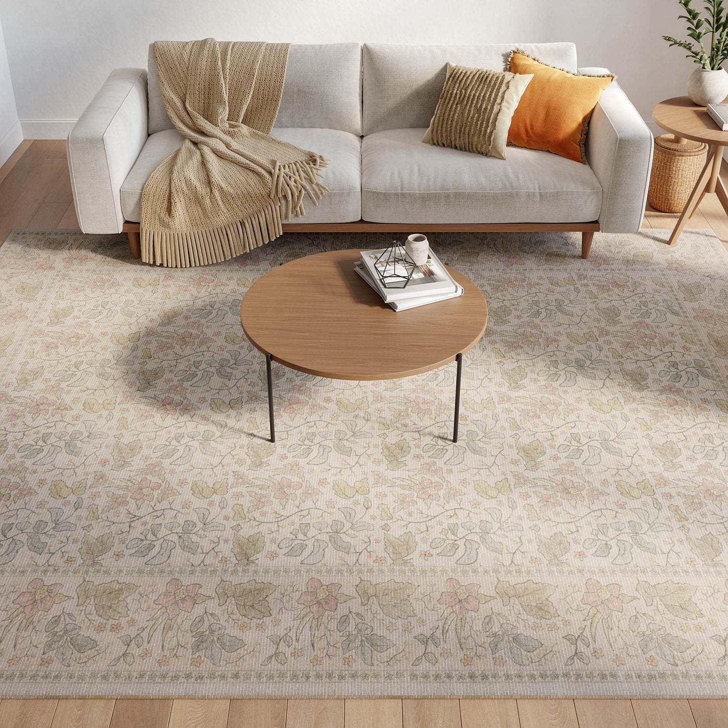 Cozy living room with a floral beige rug under a round wooden coffee table, light gray sofa, beige throw, and orange striped cushions.